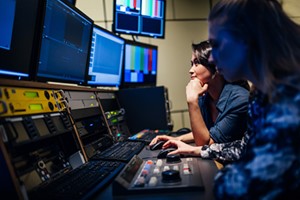 women watching monitors in control room