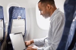 man using laptop on airplane