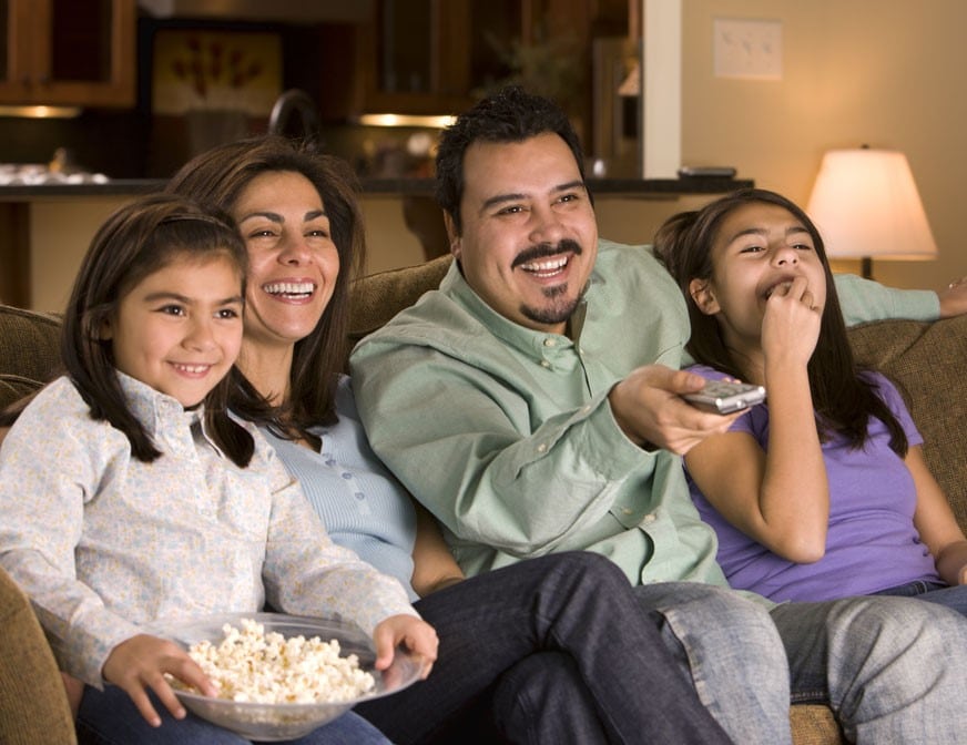 latin american family watching tv at home