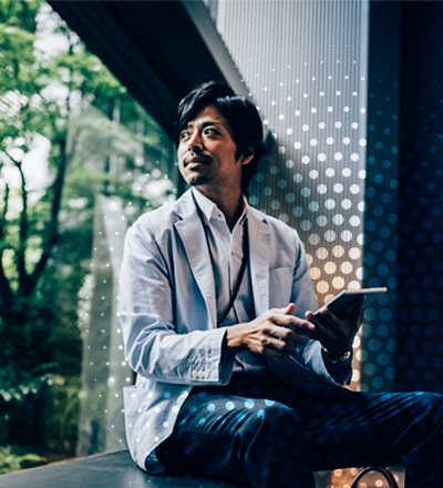man sitting holding tablet, looking out a window