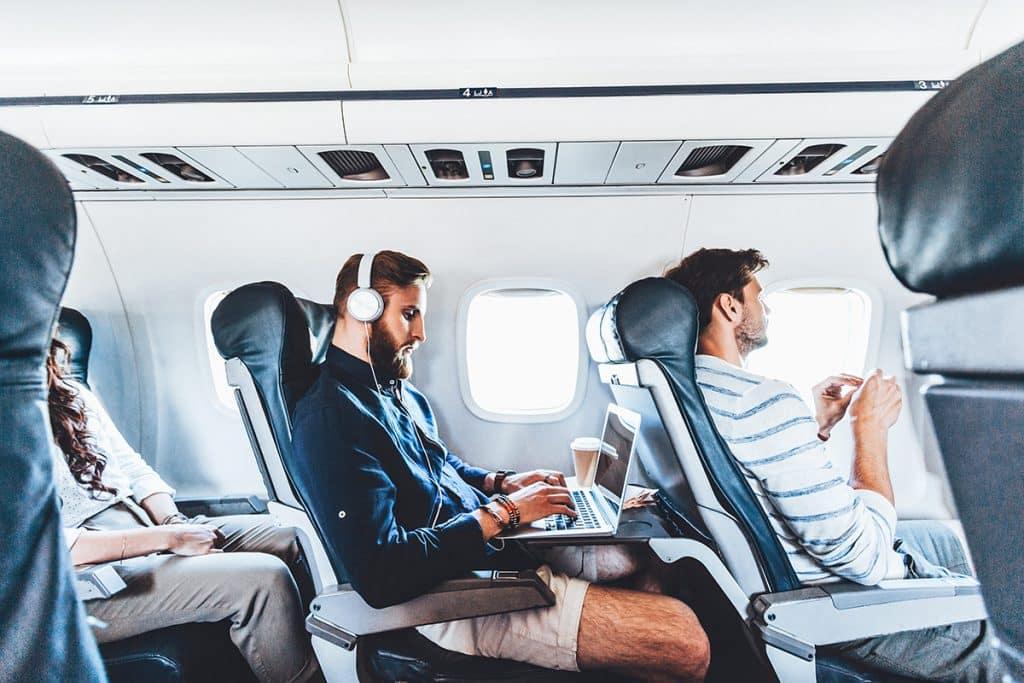 inflight experience, passenger with headphones using laptop