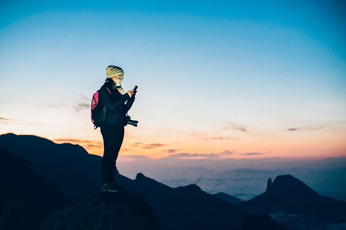 woman on mountain using multi-orbit satellite internet